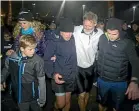  ?? GRANT MATTHEW/STUFF ?? Kiwi adventurer Scott Donaldson, with wife Sarah and son Zac, is helped ashore at Nga¯ motu Beach after his arrival to New Zealand last Monday evening.