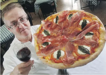  ?? FILES ?? Fedele Ricioppo holds up one of his Stuzzichin­a pizzas with prosciutto, tomatoes and bocconcini cheese at Il Centro restaurant.