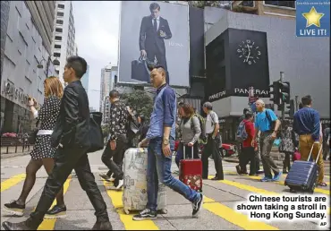  ?? AP ?? Chinese tourists are shown taking a stroll in
Hong Kong Sunday.