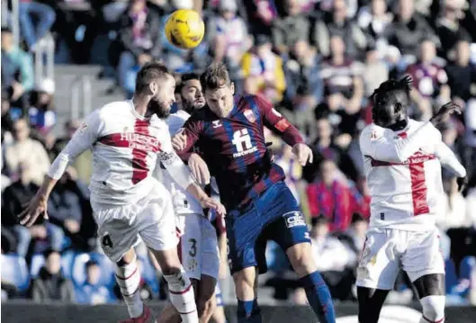  ?? LALIGA ?? Los jugadores de la SD Huesca Jorge Pulido, Iván Martos y Obeng, todos de blanco, pugnan por el esférico ante el futbolista del Eldense Carlos Hernández.