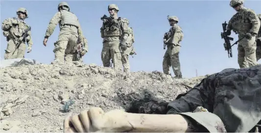  ?? Shah Marai / AFP ?? Soldats nord-americans inspeccion­en el terreny al costat del cos sense vida d’un terrorista suïcida a la localitat afganesa de Maidan Shar.