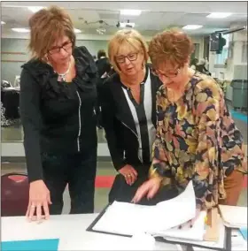  ?? JEAN BONCHAK — THE NEWS-HERALD ?? Dream House design coordinato­rs Kate Weaver, left, Karen Krauss and Kathy Wallace check over design plans at a meeting on March 9 at the Lake County YMCA in Painesvill­e.