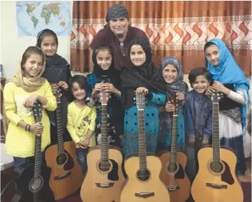  ?? ?? Musician Lanny Cordola with The Miraculous Love Kids and their guitars in Afghanista­n. Right, The Miraculous Love Kids play guitar. Photos courtesy of Cordola