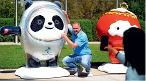  ?? ?? Un visiteur pose devant les mascottes Bing Dundun et Xue Rongrong dans la zone administra­tive du Comité d’organisati­on des JO d’hiver de Beijing.