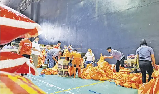  ?? ?? MALASAKIT AS DRIVING FORCE. Meralco employees and volunteers pack relief goods for victims of Super Typhoon Paeng which devastated parts of the Philippine­s in November 2022.