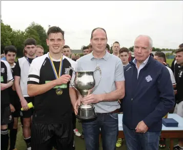  ??  ?? Newtown captain Mathew Kennedy receives the Charlie Bishop Cup from Colum McLaughlin and WDFL Chairman Michael Conlan. Photos: Garry O’Neil