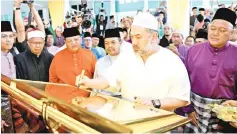  ??  ?? Yang di-Pertuan Agong Sultan Muhammad V signing on a plaque to officially open the Sultan Muhammad V Mosque at Kampung Lajau.