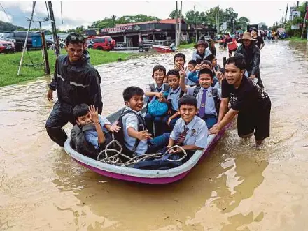  ?? NSTP PIC BY AHMAD UKASYAH ?? Stranded pupils being evacuated on a Fire and Rescue Department boat after school in Kampung Sungai Serai, Hulu Langat, yesterday.