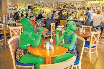  ?? L.E. Baskow Las Vegas Review-journal @Left_eye_images ?? Invader Q-tip, left, and Invader Stink enjoy a hot sauce breakfast Friday at Little Al’le’inn during Alienstock in Rachel.