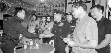  ??  ?? Saiful Bahri (centre) greeting a member of the public during the crime awareness drive. Lau is at front right. – Bernama photo