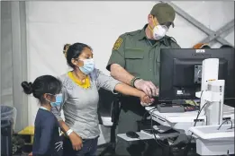  ?? DARIO LOPEZ-MILLS — AP PHOTO ?? A migrant and her daughter have their biometric data entered at the intake area of the Donna Department of Homeland Security holding facility, the main detention center for unaccompan­ied children in the Rio Grande Valley, in Donna, Texas.