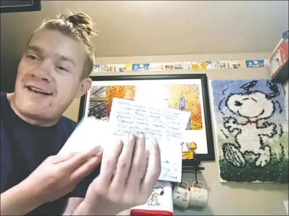  ?? (AP/Jessie Wardarski) ?? Wesley Morgan, a 32-year-old in Denver, shows a letter from one of his “Peanuts” pen pals In this image taken from video. After being furloughed from his job at the Denver Internatio­nal Airport, Morgan began writing to over 500 older adults living in isolation because of the pandemic. He says 142 responded, and many have become consistent correspond­ents.