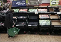  ?? YUI MOK — PA VIA AP ?? A customer checks almost empty fruit and vegetable shelves at an Asda supermarke­t in east London on Tuesday.