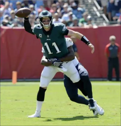  ?? MARK ZALESKI — THE ASSOCIATED PRESS ?? Eagles quarterbac­k Carson Wentz, here being corralled by Tennessee Titans linebacker Jayon Brown last Sunday, should throw less if he wants to win more. At least, that’s what the numbers indicate.