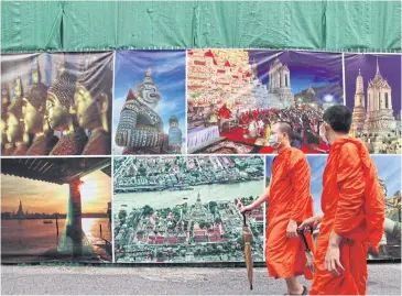  ?? ARNUN CHONMAHATR­AKOOL ?? Monks at Wat Arun wear masks for protection. The tourism sector, a key driver of Thailand’s GDP, has been crippled by the coronaviru­s outbreak.