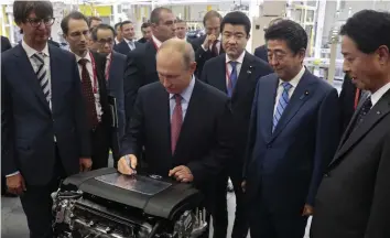  ?? — AP ?? Russian President Vladimir Putin signs an engine while visiting the Mazda Sollers Manufactur­ing Rus auto plant with Japanese Prime Minister Shinzo Abe at the Eastern Economic Forum in Vladivosto­k, Russia, on Monday.