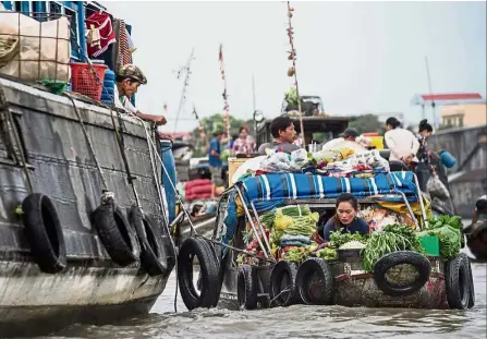  ?? — AFP ?? Staying alive: A vendor arranging her vegetables on a boat in a canal off the Song Hau river in the floating Cai Rang market, Can Tho.