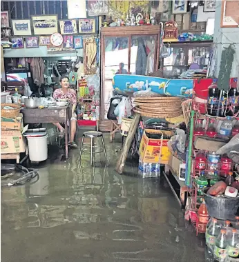  ??  ?? OPEN FOR BUSINESS: A convenienc­e store in Nakhon Sawan stays open amid flooding.