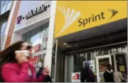  ?? MARK LENNIHAN — THE ASSOCIATED PRESS FILE ?? A woman using a cellphone walks past T-Mobile and Sprint stores in New York. T-Mobile and Sprint are trying again to combine in a deal that would reshape the U.S. wireless landscape, the companies announced Sunday