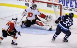  ?? The Canadian Press ?? Winnipeg Jets defenceman Dustin Byfuglien (33) scores the winning goal in overtime on Calgary Flames netminder Jeff Glass as Dillon Dube gives chase during NHL preseason action in Winnipeg on Friday night. The Jets won 4-3.