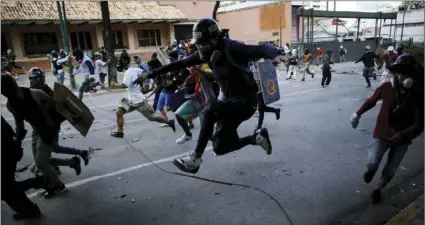  ??  ?? Anti-government protesters run from advancing Venezuelan Bolivarian National Guard officers on the first day of a 48-hour general strike in protest of government plans to rewrite the constituti­on, in Caracas, Venezuela, on Wednesday. President Nicolas...