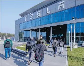  ?? EBRAHIM NOROOZI, THE ASSOCIATED PRESS ?? People walk to the Tesla Gigafactor­y for electric cars in Gruenheide, near Berlin, Germany. After reporting poor first-quarter sales, Tesla is planning to lay off about 14,000 employees as it tries to cut costs.