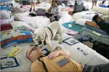  ??  ?? Jordy Gronkiewic­z and his English bulldog, Chunk, rest on an air mattress at a shelter at St. Thomas Presbyteri­an Church in Houston.