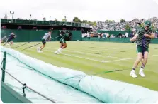  ?? GETTY/ANSA ?? I raccattapa­lle che coprono il campo appena comincia a piovere, le file per entrare, le fragole: Wimbledon ha le sue tradizioni