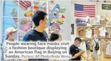  ?? Picture: AP Photo/Andy Wong ?? People wearing face masks visit a fashion boutique displaying an American flag in Beijing on Sunday.