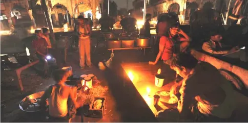  ??  ?? An Indian man prepares a meal as others sit at a roadside shop on a dark street following a power outage near a railway station in Allahabad. Electrific­ation has been on government agendas since the country’s independen­ce from colonial rule, but it has...