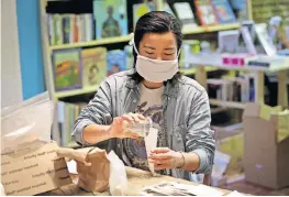  ??  ?? Volunteer Shelby Kim fills an envelope with cherry tomato seeds April 22 inside the Making Worlds bookstore in Philadelph­ia. A group of volunteers is packing up tens of thousands of seeds to ship to gardeners across the country.