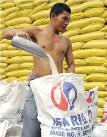  ??  ?? A WORKER repacks imported rice grains at a National Food Authority warehouse in Quezon City.