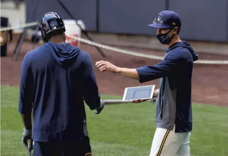  ?? DYLAN BUELL / GETTY ?? Brewers manager Craig Counsell (right) speaks with Lorenzo Cain during summer workouts at Miller Park in Milwaukee on July 4.