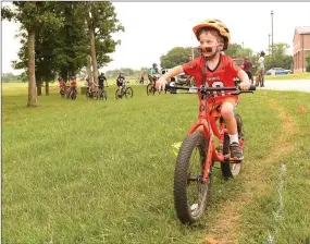  ??  ?? Klay Templeton, 4, risks losing his sunglasses as he bikes Saturday along the new trail near Pea Ridge High School. Dozens of bike riders, mostly team members in the National Interschol­astic Cycling Associatio­n, formed the trail by riding the route...