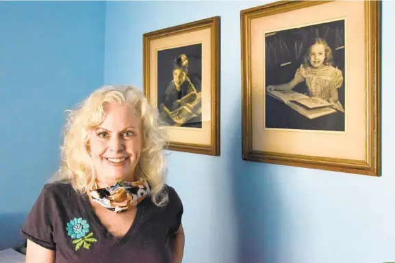  ?? AMY DAVIS/BALTIMORE SUN PHOTOS ?? Debra Stoll at her Medfield home, with 1946 portraits of her uncle, Howard Gruber, and her mother, Barbara Gruber, taken by A. Aubrey Bodine for the Enoch Pratt Library Children’s Book Week series.