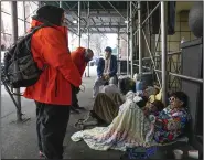  ?? (AP/Seth Wenig) ?? Recent migrants to the United States lie on the sidewalk with their belongings Monday, as they talk to city officials in front of the Watson Hotel in New York.