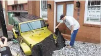  ?? KEVIN RECTOR/BALTIMORE SUN ?? Gov. Larry Hogan inspects a sunken vehicle. Hogan declared a state of emergency Sunday and directed the Maryland Emergency Management Agency to assist in Ellicott City’s recovery.