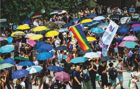  ?? AFP ?? Pro-democracy activists use umbrellas to shelter from the rain as they gather in Hong Kong’s Civil Square, yesterday, during a protest march to coincide with the 21st anniversar­y of the city’s handover from British to Chinese rule.