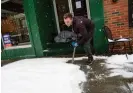  ?? ?? A restaurant worker shovels a sidewalk in Brattlebor­o, Vermont, as a person who is facing homelessne­ss sleeps in a doorway during a snowstorm on 23 March 2024. Photograph: Kristopher Radder/AP