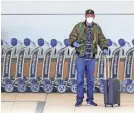  ?? JOE BURBANK/AP ?? A traveler dons a mask and gloves at Orlando Internatio­nal Airport in Florida. The number of airline passengers continues to decline across the country.