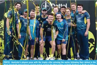  ?? — AFP ?? PERTH: Australia’s players pose with the trophy after winning the series following their defeat in the third Twenty20 internatio­nal cricket match against the West Indies at Perth Stadium in Perth on February 13, 2024.