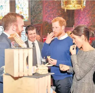  ?? Ben Birchall ?? > Prince Harry and Meghan Markle taste traditiona­l Welsh cakes during a visit to Cardiff Castle on Thursday