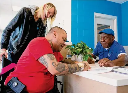  ?? Photos by Yi-Chin Lee/Staff photograph­er ?? Residents Ricardo Manriquez, center, and husband Aaron Boothe sign to get bus passes to run errands at the front desk of Houston’s new navigation center, where people moved out of an encampment can live as they await permanent housing.