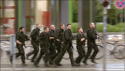  ?? AP ?? German police rush through a Munich street Friday as they search for a gunman who opened fire in a crowded mall.