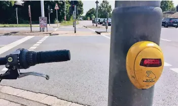  ?? RP-FOTO: SABINE SCHMITT ?? Warten auf Grün: Der Druckknopf der Fußgängera­mpel an der Einmündung Baumberger Chaussee/Opladener Straße in Monheim funktionie­rt mal – und mal nicht. Immerhin ist das gelbe Ding vandalismu­ssicher.