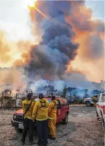  ?? Peter DaSilva / San Francisco Chronicle ?? Firefighte­rs assess a blowup through a re-burn area after winds kicked up flames Saturday east of Sonoma, Calif. Winds gusting up to 40 mph were expected through the night.