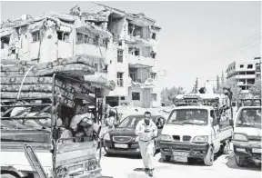  ?? YOUSSEF BADAWI, EUROPEAN PRESSPHOTO AGENCY ?? Syrian citizens return with their belongings to the town of al-Husseinia on Aug. 16.