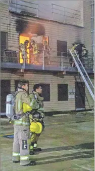  ??  ?? Firefighte­rs add wood inside the training building to build up the flames while others waited to begin.