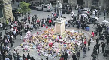  ?? Christophe­r Furlong Getty Images ?? PEOPLE GATHER in Manchester around f loral tributes to the bombing victims before a vigil by religious leaders from across the city. Sixty-four people remained hospitaliz­ed, 20 of whom had life-changing injuries.