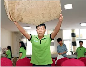  ??  ?? A student majoring in hospitalit­y and hotel management practices laying a tablecloth.